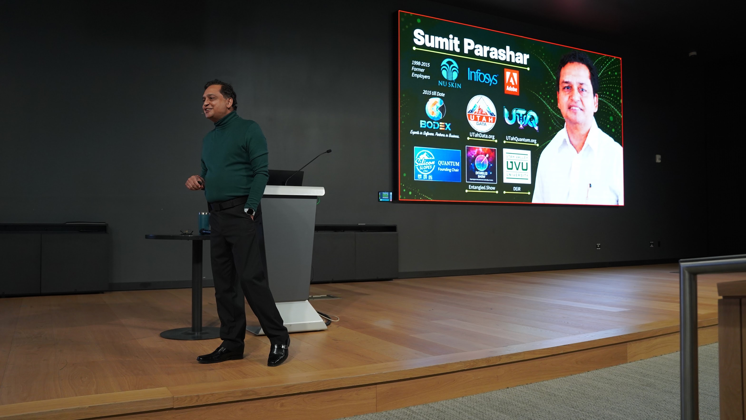 Sumit Parashar speaking on stage at Utah Valley University beside a slide introducing his professional background.